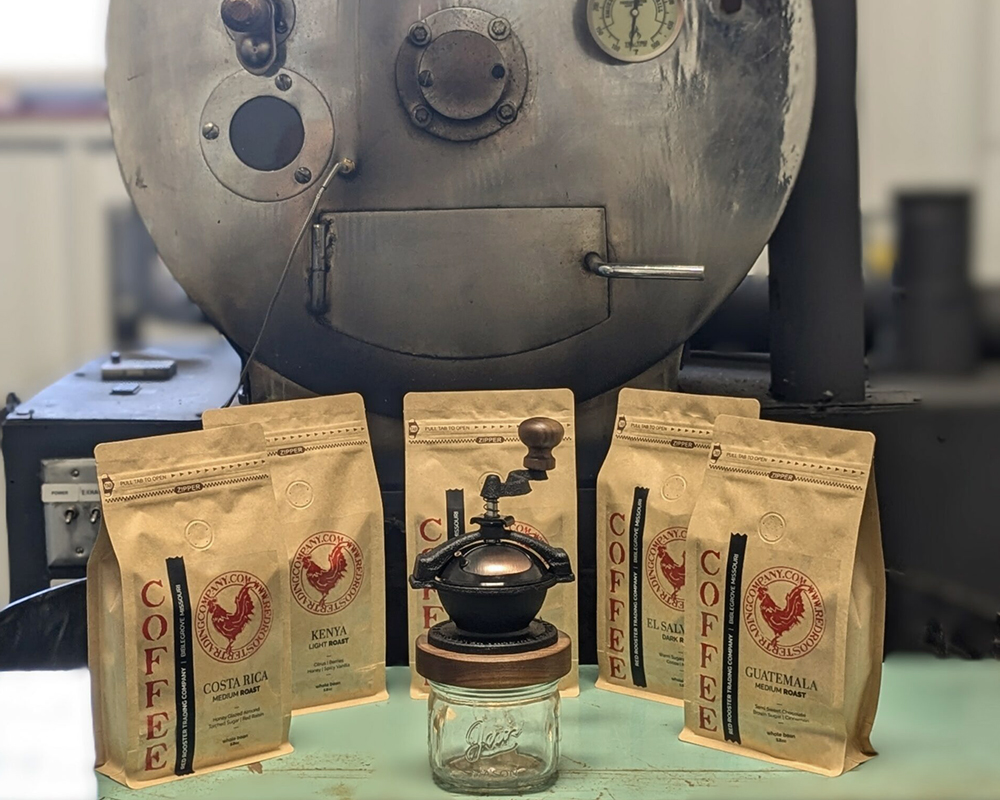 Bags of Red Rooster small batch coffee with the Camano Coffee Mill in front of the coffee roaster